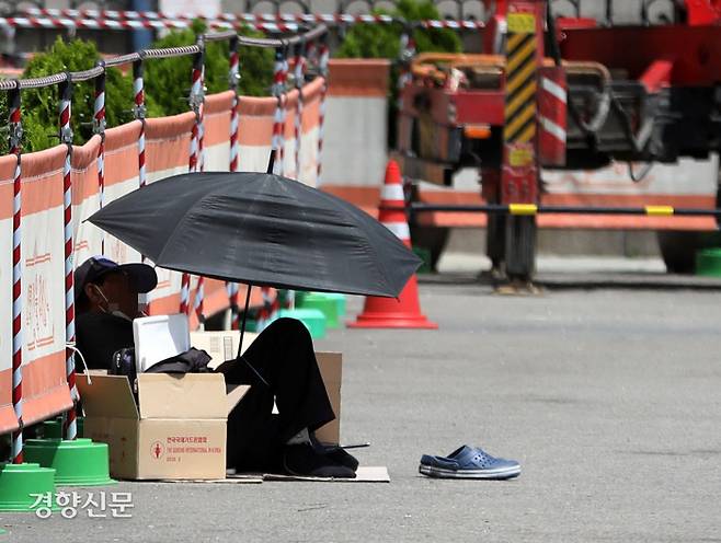 우산 아래 ‘백신 사각’ 맑고 더운 날씨를 보인 16일 서울역광장에서 한 노숙인이 우산 아래 앉아 햇빛을 피하며 쉬고 있다. 김창길 기자