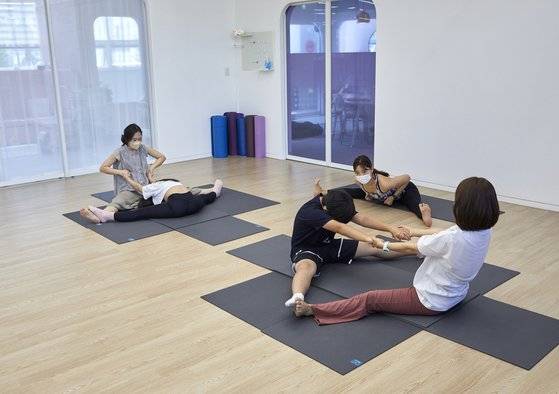 최은선 강사 구호에 맞춰 엄마와 함께 운동하는 학생기자단. 두 발을 맞대고 넓게 벌린 뒤 서로의 팔을 밀고 당기며 다리 안쪽과 허리에 오는 자극을 느껴본다.