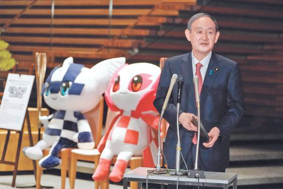 Japanese Prime Minister Yoshihide Suga, next to the mascots of Tokyo 2020 Olympic and Paralympic Games, speaks to media after announcing that Tokyo, Kyoto and Okinawa will receive pre-emergency status under a new prevention law during a government task force meeting at the Prime Minister’s Office in Tokyo on April 9, 2021. [YONHAP]