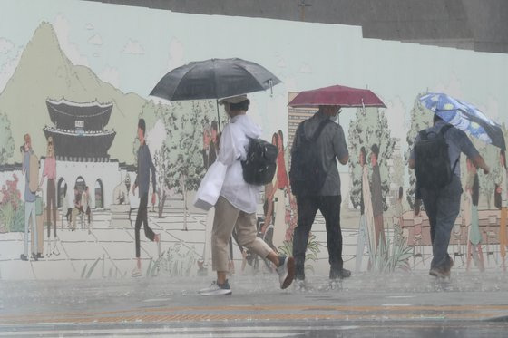 지난 23일 오후 서울 광화문광장에서 갑작스런 소나기에 우산을 쓴 시민들이 걸음을 재촉하고 있다. 연합뉴스