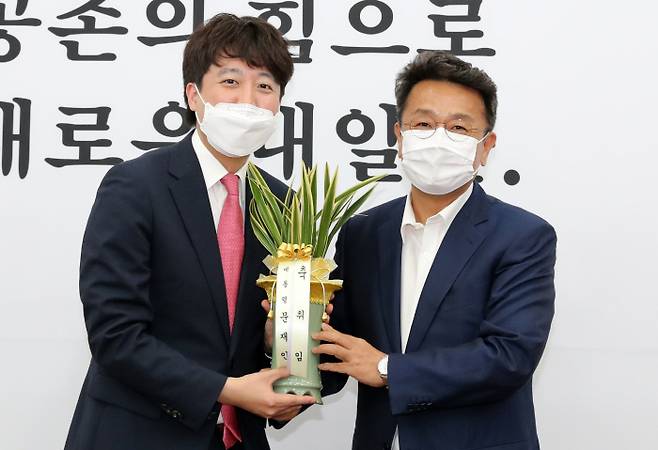 이준석 신임 국민의힘 대표(왼쪽)가 16일 국회에서 예방 온 이철희 청와대 정무수석으로부터 문재인 대통령이 보낸 난을 전달받고 있다. [이승환 기자]