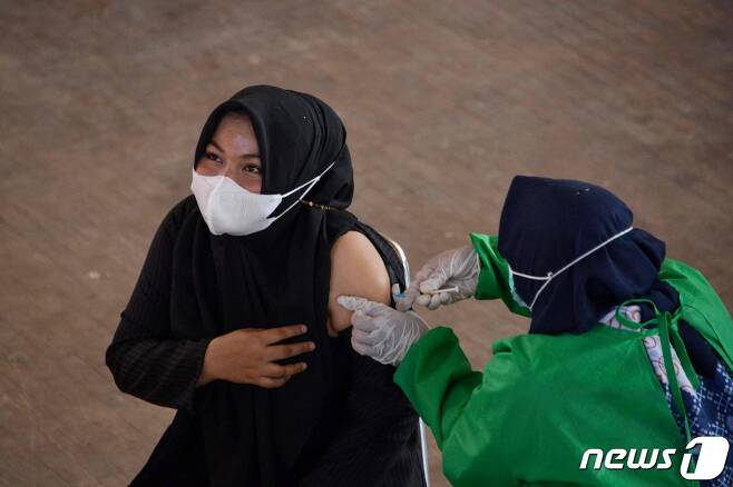 인도네시아 반다 아세 한 체육관에 마련된 신종 코로나바이러스 감염증(코로나19) 백신접종소에서 한 여성이 중국 시노백 백신을 맞고 있다.  © AFP=뉴스1