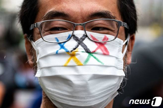 19일 도쿄올림픽 반대 시위자가 올림픽 반대를 상징하는 마스크를 쓴 채 도쿄도청에서 시위를 벌이고 있다. © AFP=뉴스1