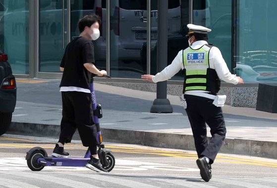 전동킥보드 등 개인형 이동장치(PM)의 이용 규제를 강화하는 개정 도로교통법 시행이 시작된 13일 서울 마포구 홍대입구역 인근 인도에서 마포경찰서 경찰들이 헬멧 없이 전동킥보드를 이용하는 시민에게 재개정 관련 내용 홍보 및 계도를 하고 있다. 경찰은 규정 변경을 홍보하는 차원에서 이날부터 한 달 동안 계도 위주의 단속을 벌일 방침이다. 2021.05.13. 김상선