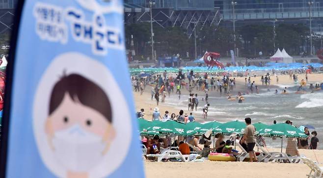 지난 11일 해운대해수욕장을 찾은 시민과 관광객들이 물놀이를 즐기고 있는 가운데 백사장에 마스크 착용을 알리는 깃발이 설치돼 있다. /사진=뉴시스