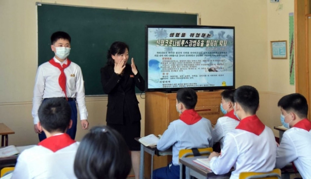 평양 락랑구역 충성초급중학교에서 지난 5월 16일 교사가 한 학생을 교실 앞에 세워 예시를 들며 마스크 쓰는 법을 가르치고 있다./연합뉴스