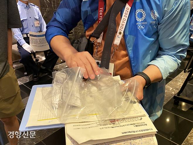 2020 도쿄올림픽 취재진이 14일 도쿄 분쿄구 미디어호텔  로비에서 대회 관계자에게 코로나19 검사 진단 키트를 전달하고 있다.  2021. 7. 14 도쿄=올림픽사진공동취재단