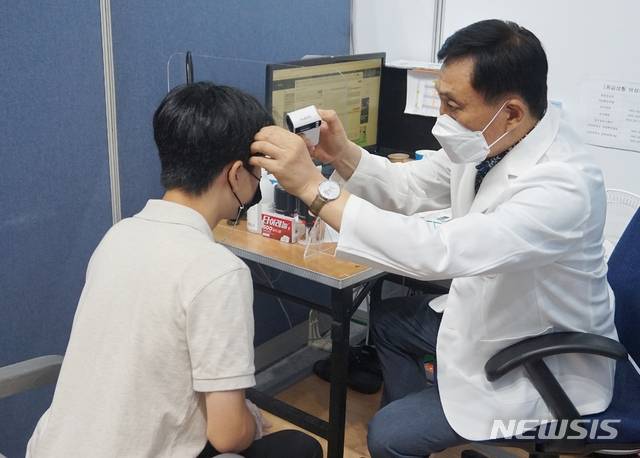 [청주=뉴시스] 김재광 기자 = 화이자 코로나19 백신 접종이 시작된 19일 오전 청주시 상당구청에 마련된 백신접종센터에서 예진 담당 의사가 고3학생의 열을 체크하고 있다.kipoi@newsis.com2021.07.19.