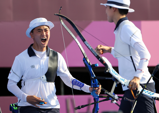 The Korean mixed team archers Kim Je-deok, left, and An San celebrate after winning gold in the mixed team archery event at the 2020 Tokyo Games at Yumenoshima Park Archery Field in Tokyo on Saturday. [YONHAP]