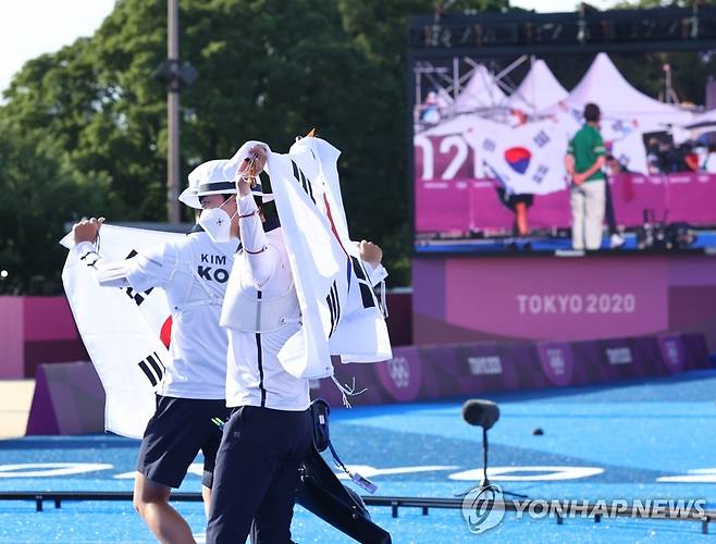 [올림픽] 도쿄에 태극기 휘날리며 (도쿄=연합뉴스) 류영석 기자 = 양궁 국가대표 김제덕과 안산이 24일 일본 도쿄 유메노시마 공원 양궁장에서 열린 도쿄올림픽 혼성 결승전에서 금메달을 획득한 후 태극기를 들고 경기장을 돌고 있다. 2021.7.24 ondol@yna.co.kr
