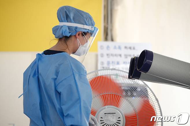 전국 대부분 지역에 폭염특보가 발효 중인 25일 서울 강남구보건소에 마련된 코로나19 선별진료소에서 한 직원이 냉풍기 바람을 쐬고 있다. 2021.7.25/뉴스1 © News1 안은나 기자