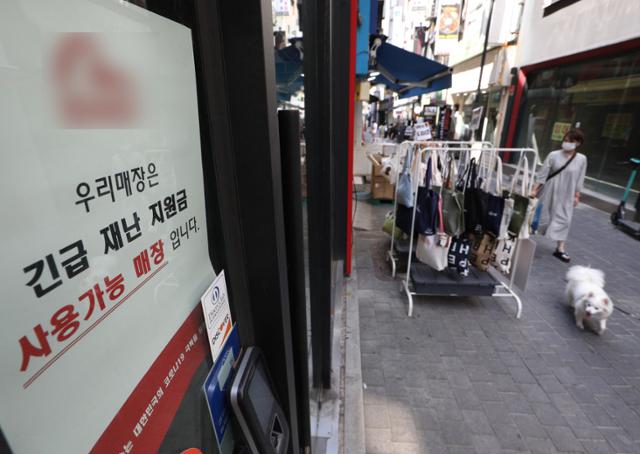 34조9000억 원 규모의 추가경정예산안이 국회를 통과한 가운데 25일 서울 명동거리의 한 매장에 재난지원금 결제가 가능하다는 안내문이 붙어 있다. 뉴스1