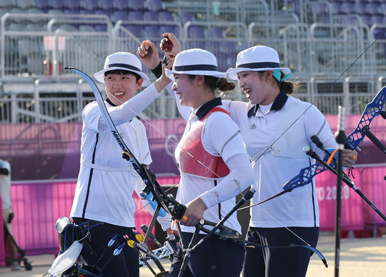 Jang Min-hee, An San and Kang Chae-young of the Korean women’s archery team celebrate after winning the gold medal match in three straight sets against Russia on Sunday at Yumenoshima Park Archery Field in Tokyo. [JOINT PRESS CORPS]