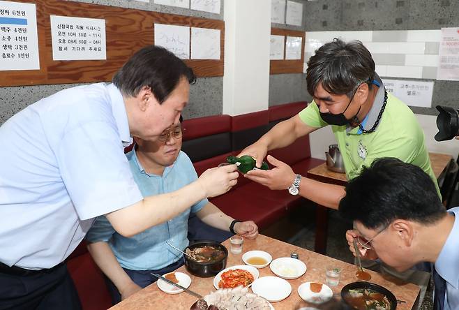 윤석열 전 검찰총장이 27일 낮 부산 서구에 있는 한 국밥집에서 국민의힘 부산 국회의원들과 식사하면서 한 시민으로부터 소주를 받고 있다. /연합뉴스