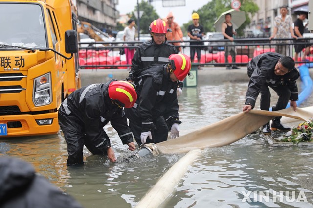 [저우산=신화/뉴시스] 25일 중국 저장성 저우산의 한 주택가에서 구조대원들이 빗물 제거 작업을 하고 있다. 2021.07.27.