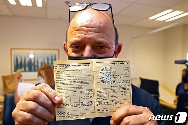 12일(현지시간) 이스라엘 텔아비브의 셰바 메디컬 센터에서 코로나19 화이자 백신을 처음으로 3번째 접종받은 시민이 증명서를 보여주고 있다. © AFP=뉴스1 © News1 우동명 기자