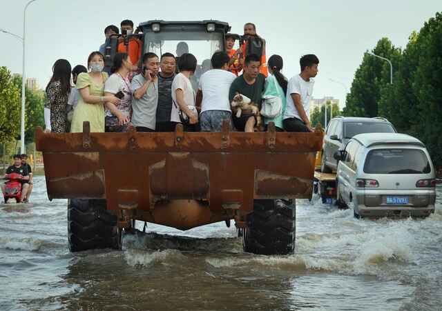지난달 25일 중국 허난성 정저우에서 주민들이 트럭 짐칸에 타고 폭우로 침수된 도로를 지나고 있다. 정저우/신화 연합뉴스
