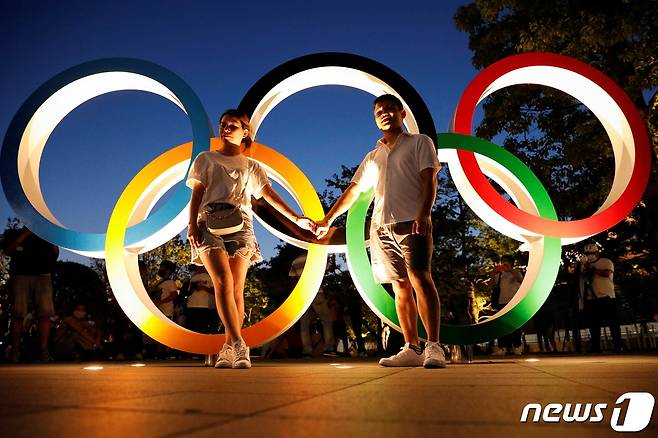 도쿄올림픽 오륜마크 앞에서 커플이 포즈를 취하고 있다. © 로이터=뉴스1 © News1 서한샘 기자