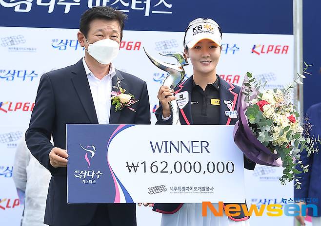 트로피와 우승 상금 1억 6,200만원 그리고 꽃다발을 받은 오지현. 김정학 제주특별자치도개발공사 사장(왼쪽)과 포토타임을 가지고 있다.