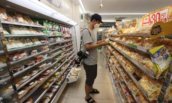 2020 도쿄올림픽 취재진이 12일 도쿄 분쿄구 미디어호텔 인근의 편의점에서 식료품을 구매하고 있다. [사진기자협회]