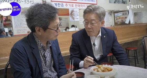 이재명 경기도지사는 경기도 이천 쿠팡 물류센터 화재를 보고받고서도 유튜브 방송 녹화를 강행했다는 비판을 받고 있다. 황교익씨와 떡볶이 '먹방' 중인 이 지사. [유튜브 캡처]