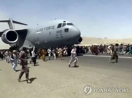 (카불 AP=연합뉴스) 16일(현지시간) 아프가니스탄 수도 카불의 하미드 카르자이 국제공항에서 미군 C-17 수송기가 이륙을 위해 활주로를 따라 이동하자 탑승하지 못한 아프간 시민 수백 명이 수송기를 따라 내달리고 있다. 탈레반이 정권 재장악을 선언하자 카불 국제공항에는 외국으로 탈출하려는 시민들이 끝도 없이 몰려들었으며 결국 항공기 운항이 중단되고 공항은 마비됐다.