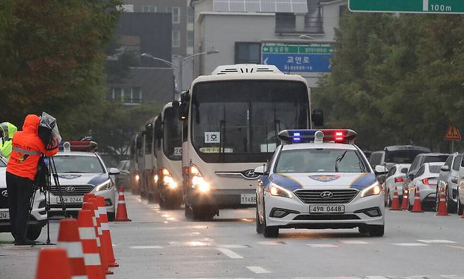 A police vehicle escorts buses transporting the Afghan nationals who recently arrived in South Korea on Friday as they enter the National Human Resources Development Institute in Jincheon, North Chungcheong Province. (Park Jong-shik/The Hankyoreh)