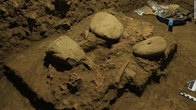 술라웨시섬의 동굴 속에서 큰 돌과 나란히 묻혀있는 여성의 골격 파편(사진=인도네시아 하사누딘대 제공)