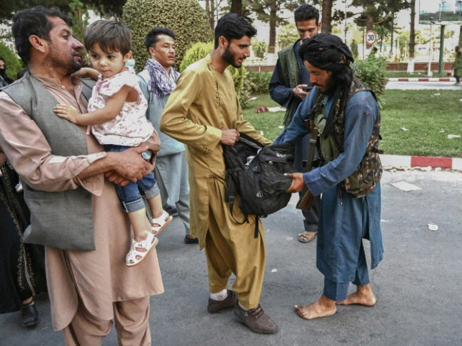 탈레반 조직원(오른쪽)이 카불 공항으로 향하는 시민들의 가방을 뒤지고 있다(사진=AFP)