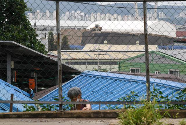 지난 2일 인천 서구 사월마을 마을회관 인근 한 주택에서 주민이 텃밭을 돌보는 가운데, 뒤쪽에 폐기물처리 공장이 보인다. 인천=홍인기 기자