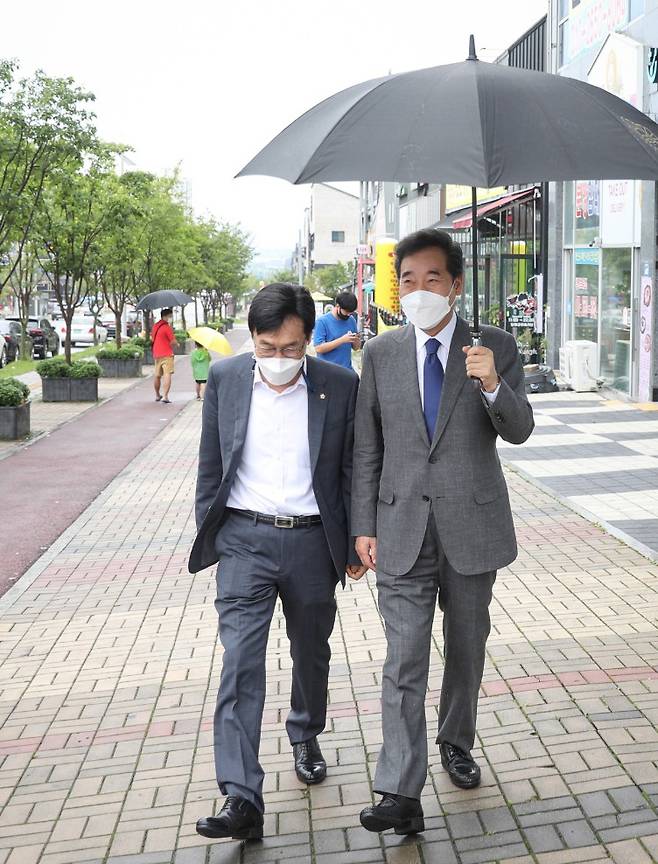 더불어민주당 대권주자인 이낙연 전 대표가 29일 충북 음성군 맹동면 임호선 국회의원 지역사무소에서 중부3군 핵심당원 간담회를 마치고 직접 우산을 들고 이장섭 의원과 함께 걷고 있다. [연합]