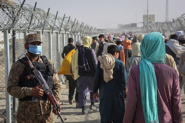 지난달 26일 아프가니스탄 피난민이 파키스탄 측이 국경 차만 검문소에 설치한 펜스를 따라 걷고 있다. 파키스탄 군인은 경계를 늦추지 않는 모습이다./AFP 연합뉴스