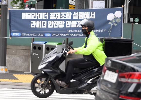 “배달라이더 안전망 만들자” - 지난 26일 서울 강남구 선릉역 인근 도로에서 화물차에 치여 사망한 오토바이 배달원을 추모하고 배달 노동자의 노동 환경 개선을 촉구하는 내용의 현수막이 29일 선릉역 앞에 걸렸다. 고인은 코로나19로 다니던 회사 사정이 어려워지면서 약 5개월 전부터 배달 일을 하다가 사고를 당했다. 전국민주노동조합총연맹 서비스연맹 서비스일반노동조합 배달서비스지부는 “배달의민족, 쿠팡이츠 등 플랫폼 기업과의 교섭에서 라이더의 안전 문제에 대해 책임을 묻고 안전보장 방안 마련을 촉구할 것”이라고 밝혔다.박윤슬 기자 seul@seoul.co.kr