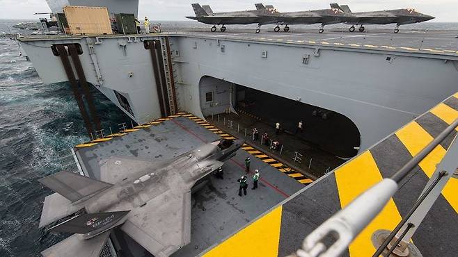 영국 항모 엘리베이터 올려진 미 해병대 F-35B 전투기가 내부 격납고에서 갑판으로 이동하고 있다. 영 해군
