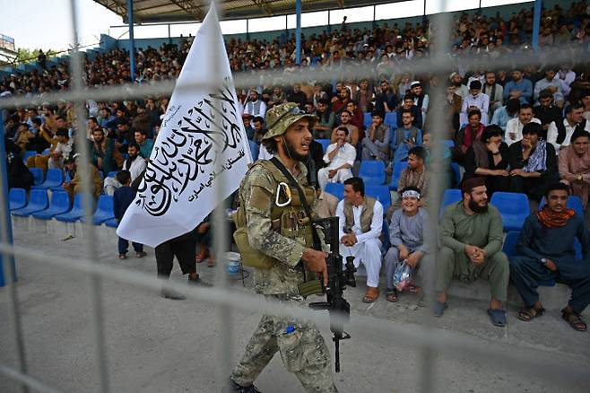 아프가니스탄 수도 카불의 국제 크리켓 경기장에서 탈레반 대원이 탈레반 깃발을 등에 꽂고 경비를 서고 있다. (사진=AFP, 연합뉴스)