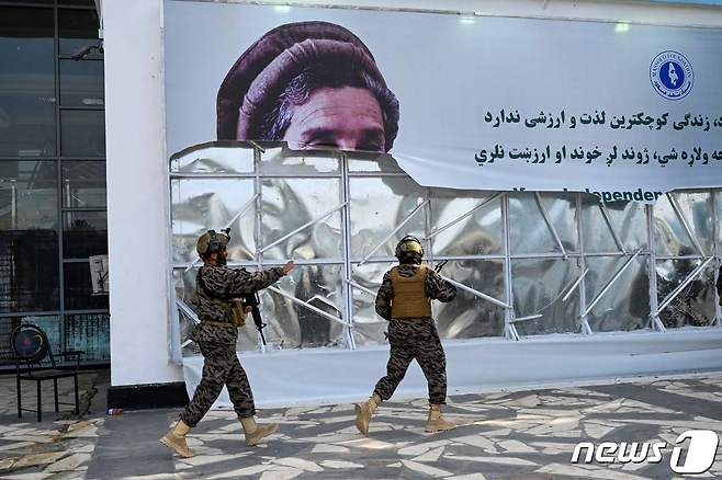 31일(현지시간) 미군이 철수를 완료한 아프가니스탄의 카불 공항에서 아프간 국부로 불리는 아흐마드 샤 마수드의 사진을 탈레반 군들이 찢고 있다. © AFP=뉴스1 © News1 우동명 기자