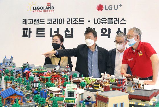황현식 LG유플러스 대표(왼쪽에서 두 번째)와 김영필 레고랜드 코리아 리조트 사장(오른쪽 첫 번째)이 9일 협약식 후 레고 브릭으로 만든 레고랜드 조감도 모형을 살펴보고 있다. LG유플러스 제공