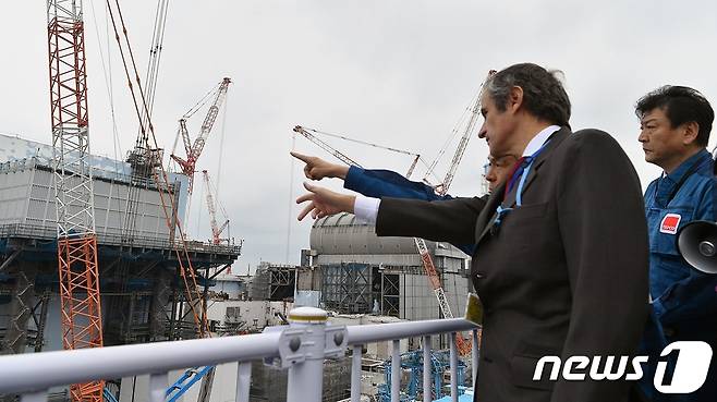 라파엘 그로시 국제원자력기구(IAEA) 사무총장이 작년 2월26일 일본 후쿠시마 제1원자력발전소 현장을 찾아 관계자들로부터 폐로 공정 및 오염수 처리 현황 등에 대한 설명을 듣고 있다. (IAEA) © 뉴스1
