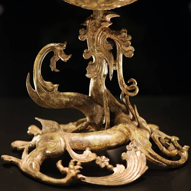 The water, symbolizing life, is expressed as a dragon on the base of the Gilt-bronze Incense Burner of Baekje. The lotus flower base blooms from the mouth of the five-legged dragon, whose legs appear like splashing waves.　Photo © 2020 Hyungwon Kang