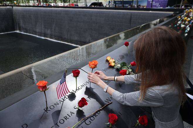 20년 전 9.11 테러로 아버지를 잃은 한 여성이 11일 9.11 테러 20주년 기념식에서 세계무역센터가 있던 자리에 조성된 '메모리얼 풀'을 찾아 희생자 명비에서 아버지의 이름을 찾아 꽃을 꽂고 있다. /AFP 연합뉴스