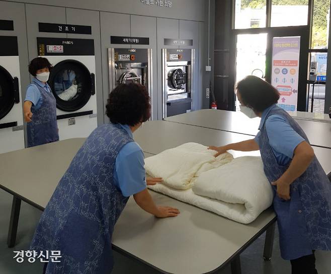 정선 ‘희망드림 행복빨래방’에서 근무 중인 할머니들이 지난 8일 사업장 건조기에서 꺼낸 이불을 작업대 위에 놓고 정리하고 있다.