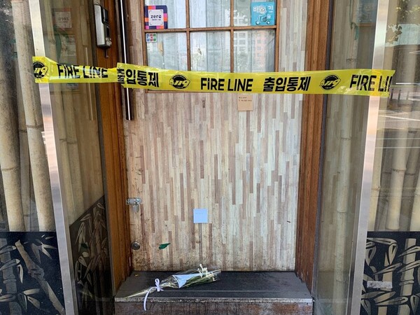 13일 지난 7일 숨진 채 발견된 자영업자 ㄱ(57)씨가 운영하던 서울 마포구의 맥줏집 문 앞에 출입 통제 테이프가 둘려 있다. 문에는 ㄱ씨를 추모하는 포스트잇이 붙어 있고, 바닥에 흰 국화가 놓여 있다.