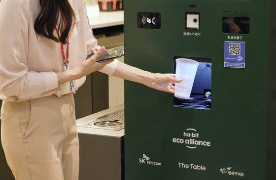 고객이 SK텔레콤 사내 카페에서 다회용컵에 음료를 받아 이용한 뒤 무인 회수기에 반납하는 모습. SK텔레콤 제공