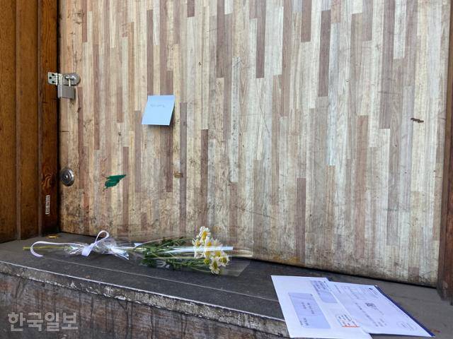 13일 오후 서울 마포구 염리동 한 맥주집 문 앞에 국화 꽃다발과 고지서가 놓여 있고 문에는 '편히 쉬세요'라는 메모가 붙어 있다. 김소희 기자