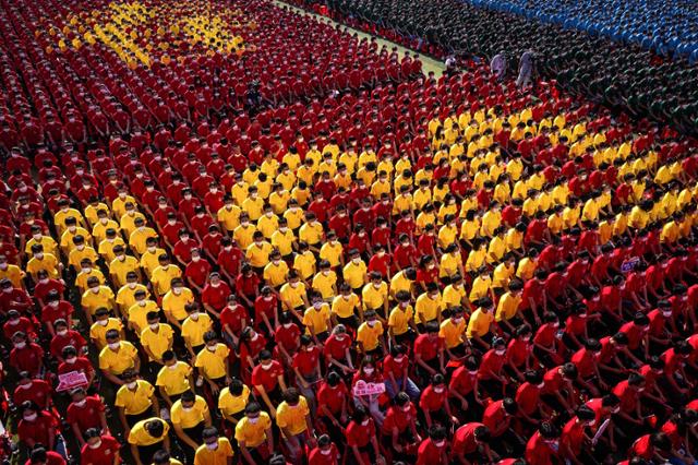 10일 중국 허베이성 우한의 대학생들이 개학식에서 복장 색깔을 이용해 공산당 창건 100주년을 가리키는 이미지를 만들고 있다. 우한=AFP 연합뉴스