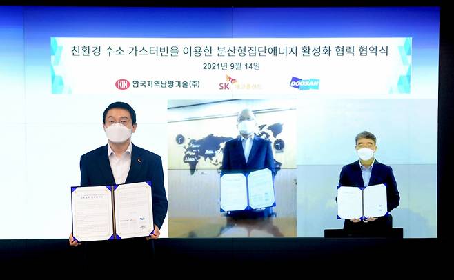 SK에코플랜트가 14일 한국지역난방기술, 두산중공업과 ‘친환경 수소 가스터빈을 이용한 분산형 집단에너지 사업’ 추진을 위한 업무협약(MOU)을 체결했다. 사진은 주양규 SK에코플랜트 플랜트사업단장(왼쪽 첫번째)과 김호기 한국지역난방기술 전무(왼쪽 두번째), 박홍욱 두산중공업 부사장이 온라인 화상 협약식을 마친 후 협약서를 들고 기념촬영을 하는 모습. 사진=SK에코플랜트