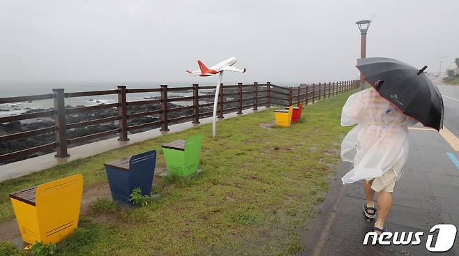 제14호 태풍 '찬투(CHANTHU)'가 북상 중인 14일 오전 제주시 용담해안도로에서 우비를 입은 행인이 발걸음을 옮기고 있다. 2021.9.14/뉴스1 © News1 오현지 기자