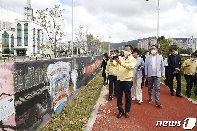 15일 울산 북구 매곡천에서 옹벽 벽화 제막식이 열린 가운데 이동권 북구청장을 비롯한 참가자들이 벽화를 둘러보고 있다. (울산 북구 제공) © 뉴스1
