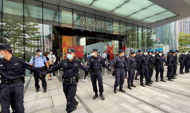 13일 중국 선전 헝다그룹 본사 앞에 '돈을 돌려달라'면서 몰려든 시위대를 막기 위해 경비원들이 줄지어 서있다./로이터 연합뉴스