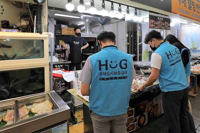 주택도시보증공사(HUG) 직원들이 시장을 방문해 구입할 물품을 고르는 모습. [HUG 제공]